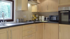 Une cuisine avec des meubles de rangement en bois, une cuisinière à gaz, un four à micro-ondes et un évier.