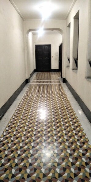 A hallway with a patterned floor and a black door at the end.