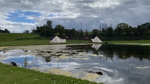 Un terrain de camping avec deux tentes et un étang.