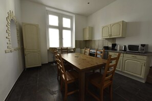 A compact kitchen with a wooden dining table and chairs, a stove, and a microwave.