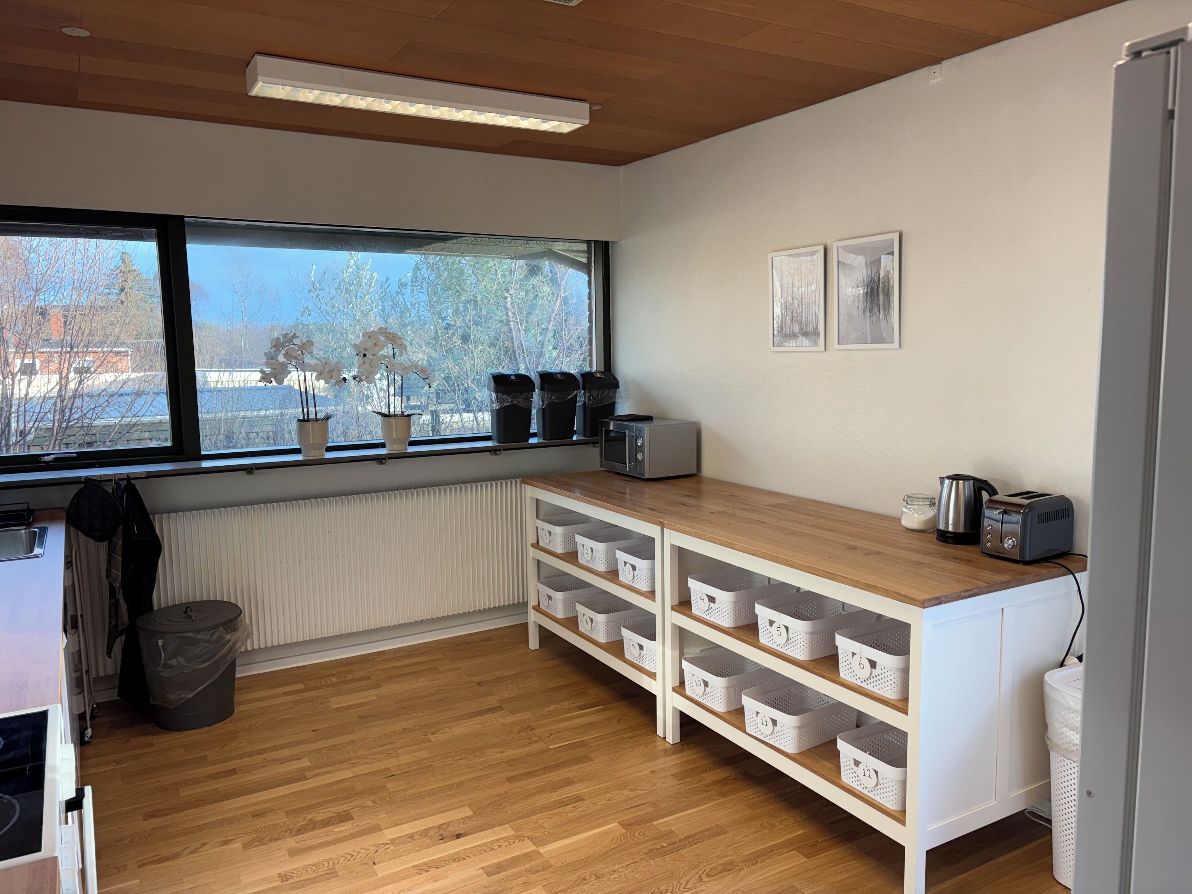 Eine Küche mit Holzausstattung, einem Fenster mit Blumentöpfen, einem Wasserkocher und einem Toaster.