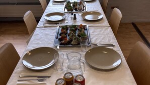 Mesa de comedor preparada para seis personas, con platos, cubiertos y bebidas.