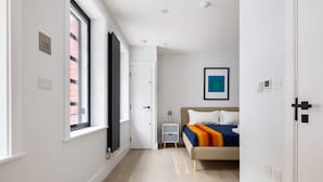 Ein modernes Schlafzimmer mit Bett, Nachttisch und Fenster.