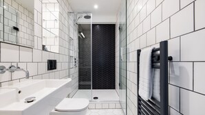 Ein modernes Badezimmer mit einem weißen Waschbecken, einer Toilette und einer Duschkabine.