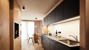 Une cuisine moderne avec des meubles de couleur sombre, un évier en acier inoxydable et un coin repas en bois.