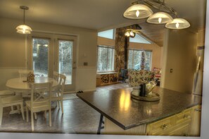 Enjoy meals in this well-equipped kitchen with a central island, dining table, and chandelier.