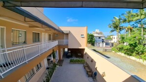Un edificio de varios niveles con balcones, un patio empedrado y zonas verdes circundantes.