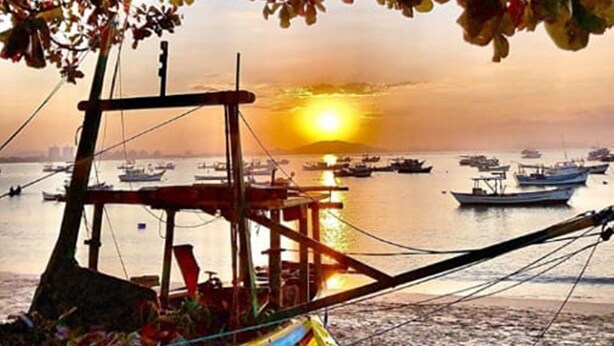 Un barco amarrado en un muelle con un atardecer de fondo.
