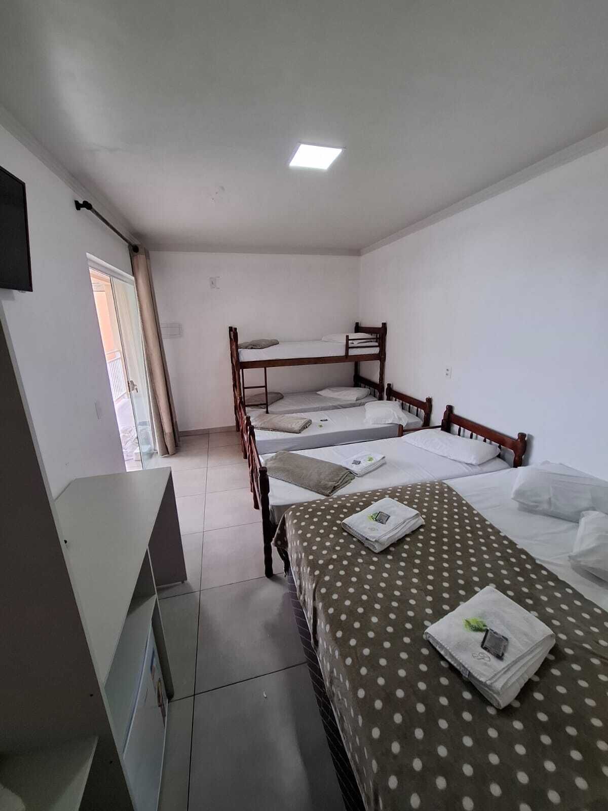 A dormitory room with bunk beds, a desk, and a ceiling light.
