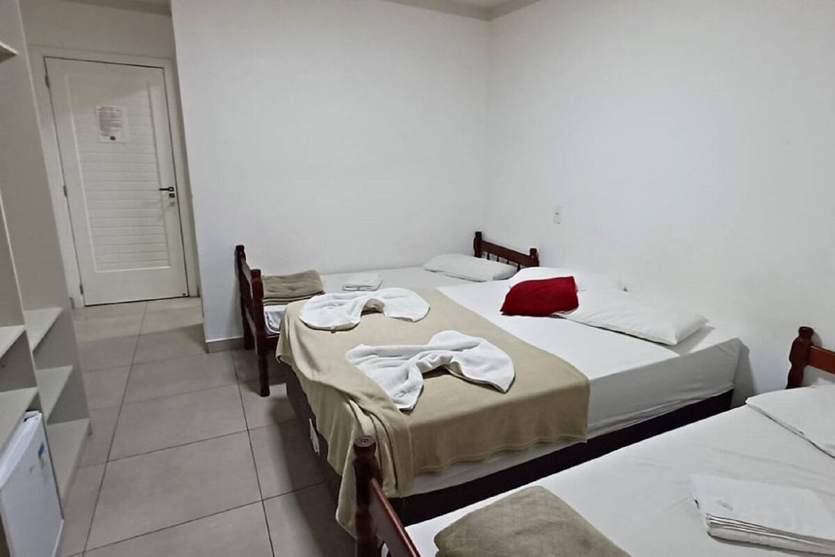 A small, clean room with two single beds, a desk, and a chair.