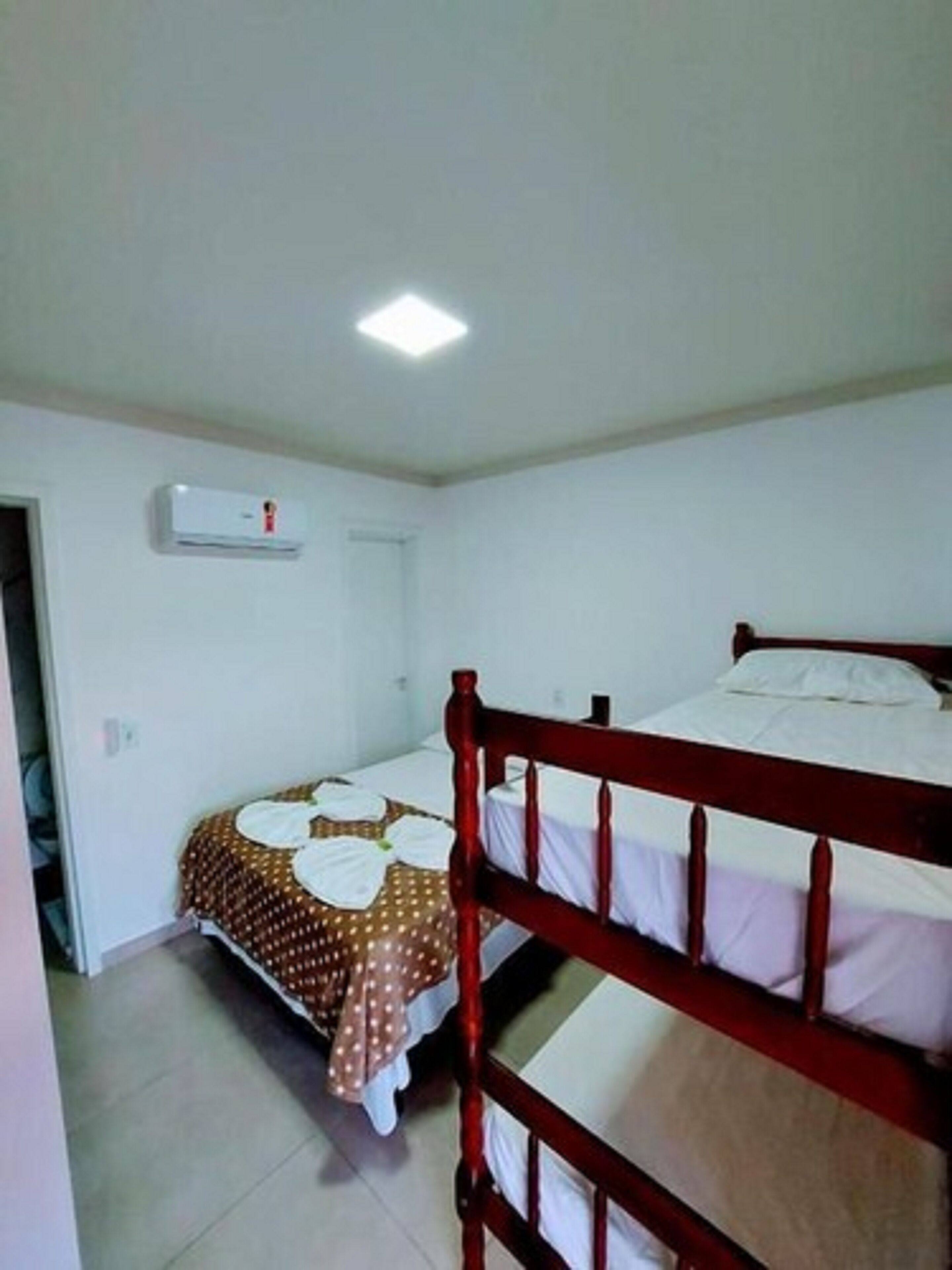 Una habitación pequeña y limpia con dos camas, un ventilador de techo y aire acondicionado.