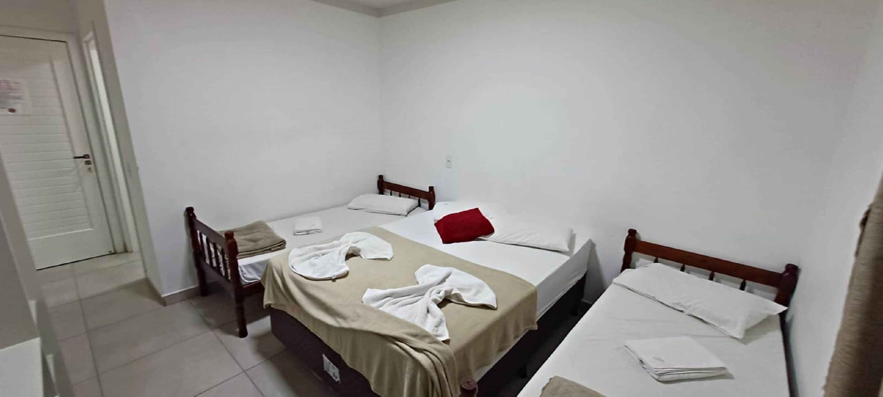 A small, clean room with two single beds, a wooden chair, and a door.