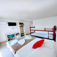 Una habitación de hotel con literas, un escritorio con silla, un televisor y un armario.