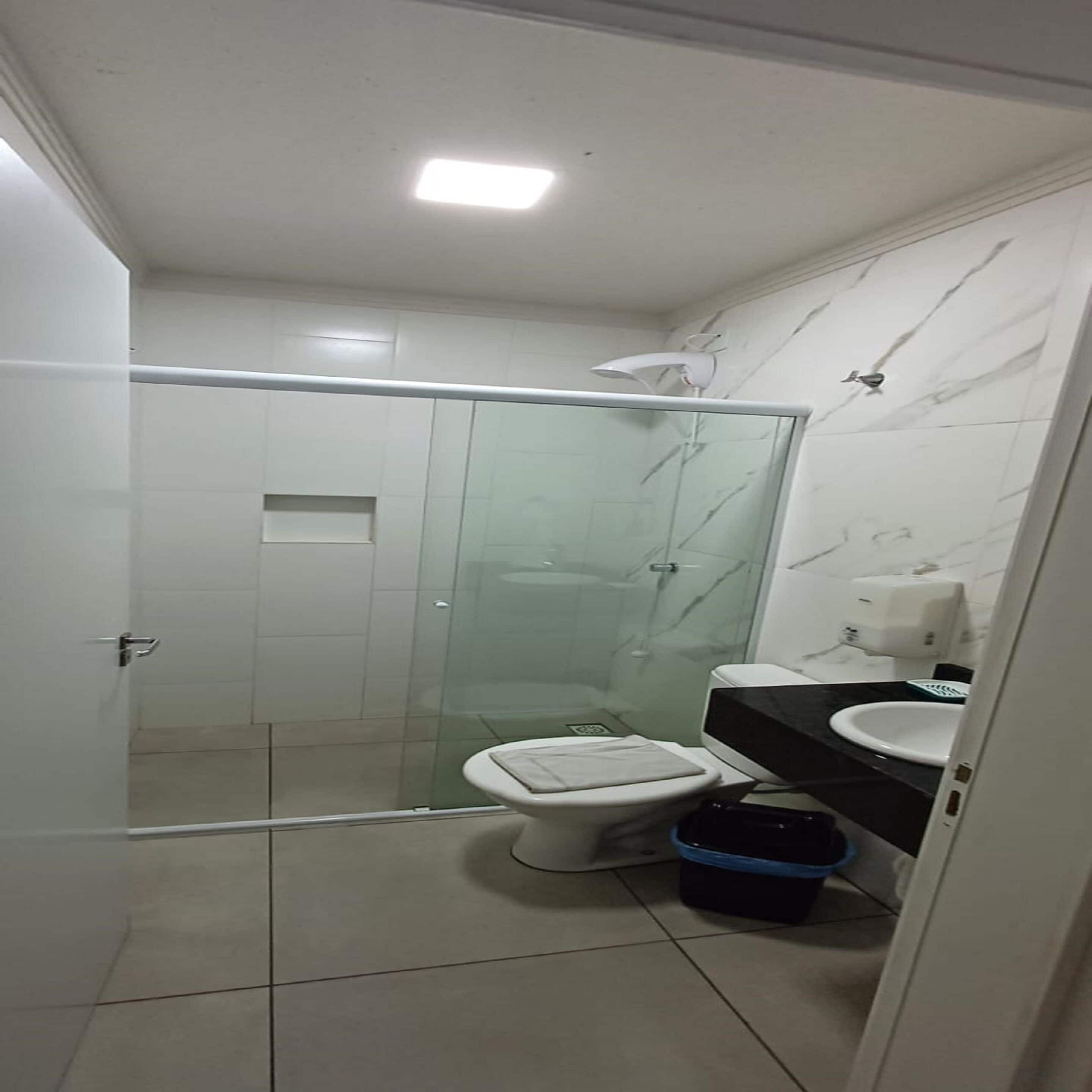 Un baño moderno con ducha acristalada, inodoro y lavamanos.