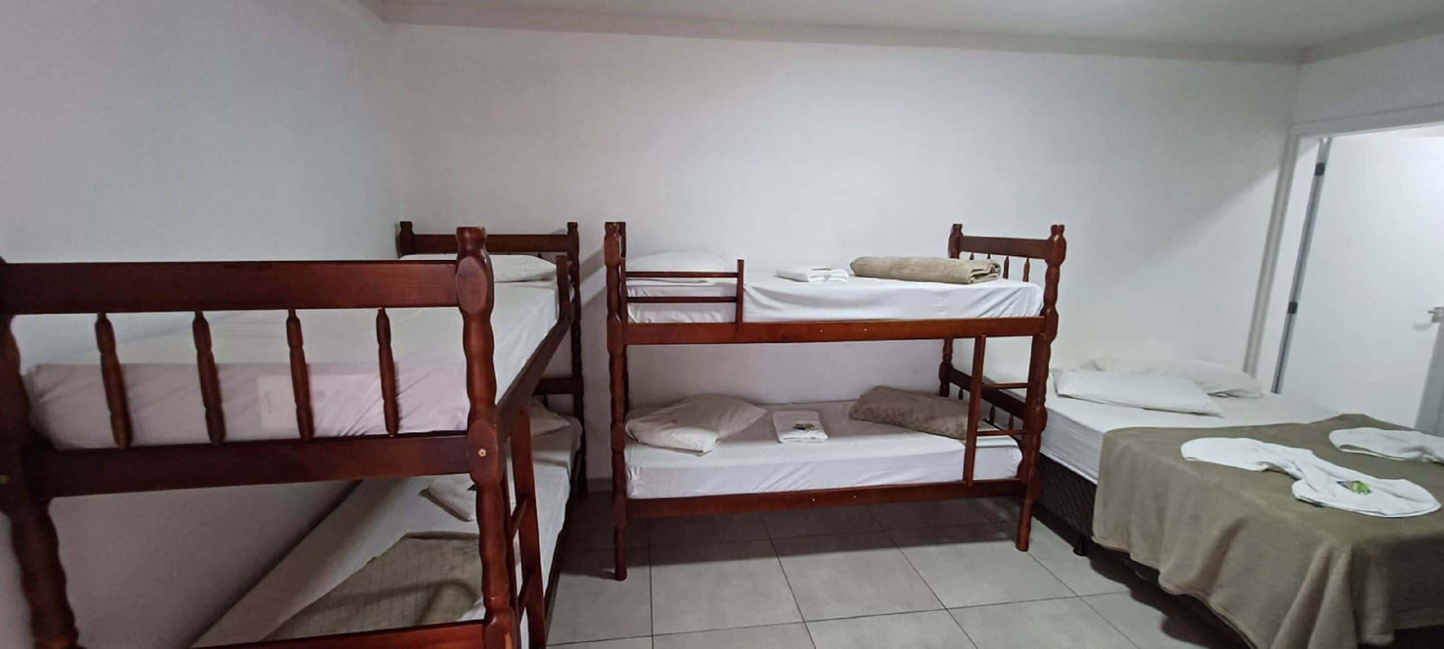A room with three wooden bunk beds, a small table with a cloth, and a door.