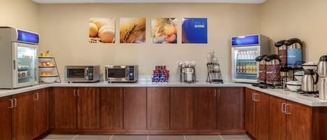 A modern kitchen with a microwave, toaster, coffee maker, and a refrigerator.
