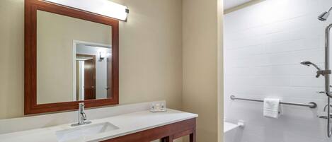 A bathroom with a white sink, a mirror with a wooden frame, a towel rack, and a shower area.
