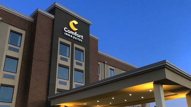 Ein Comfort Inn & Suites Gebäude mit modernem Design, mit auffälligem Logo an der Fassade, einer überdachten Eingangspforte und zahlreichen Fenstern.