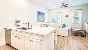 A modern kitchen with a central island, white cabinetry, and a built-in dishwasher.