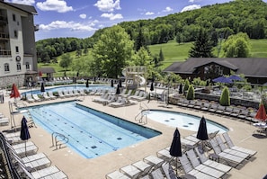 Un espace piscine avec des chaises longues, un toboggan et une vue sur un paysage verdoyant.