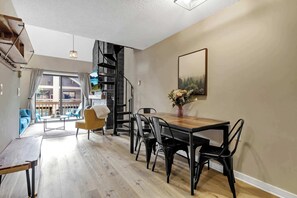 Un intérieur moderne comprenant un coin repas, un escalier et une vue dégagée sur l’extérieur grâce à une grande fenêtre.