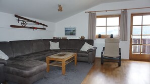 A living room with a brown leather sofa, a wooden coffee table, a beige armchair, and skis mounted on the wall.