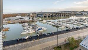 A marina with boats docked, a bridge in the background, and a road running alongside. - B&B HOTEL Bordeaux Bassins à flot (Bordeaux)