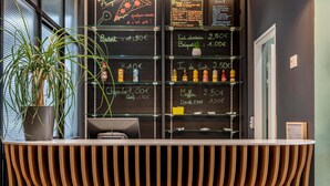 A reception desk with a chalkboard menu listing prices for items like 'Badoot' and 'Muffa'. - B&B HOTEL Bordeaux Bassins à flot (Bordeaux)