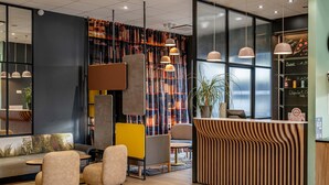A modern interior with a reception desk, seating area, and large windows. - B&B HOTEL Bordeaux Bassins à flot (Bordeaux)