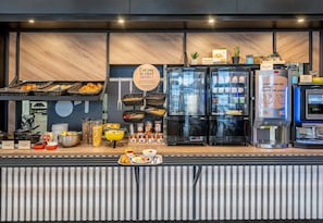 Un buffet de petit-déjeuner proposant une variété d'aliments, une machine à café et un réfrigérateur.