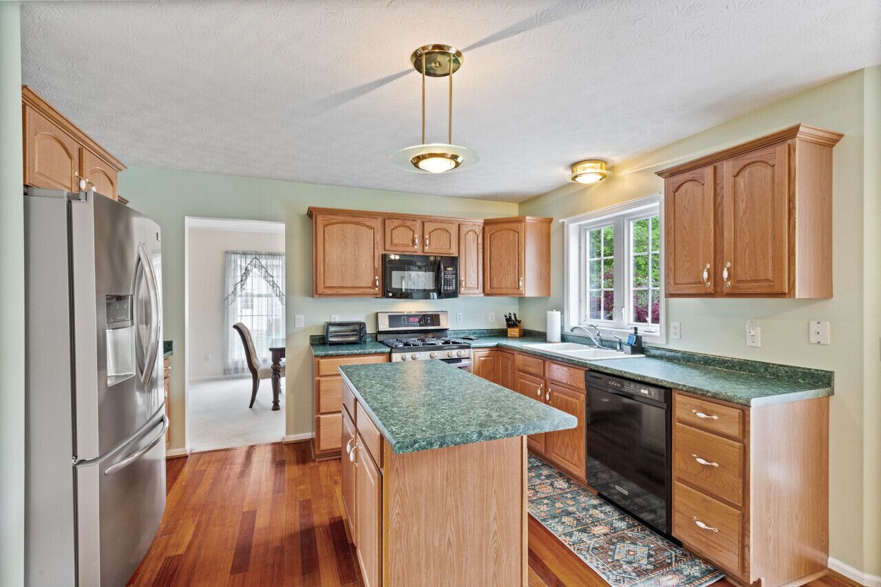 A modern kitchen with wooden cabinets, a stainless steel refrigerator, a microwave, and a dishwasher.