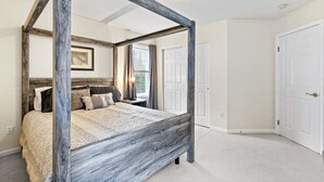 A four-poster bed with a rustic wooden frame, a quilted bedspread, and a nightstand with a lamp. - Large Family Home in Heart of Brockport (Brockport)