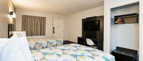 A hotel room with two beds, a desk, a chair, a television, and a coat rack.