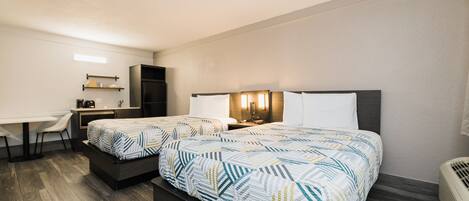 A hotel room with two beds, a desk, and a chair.