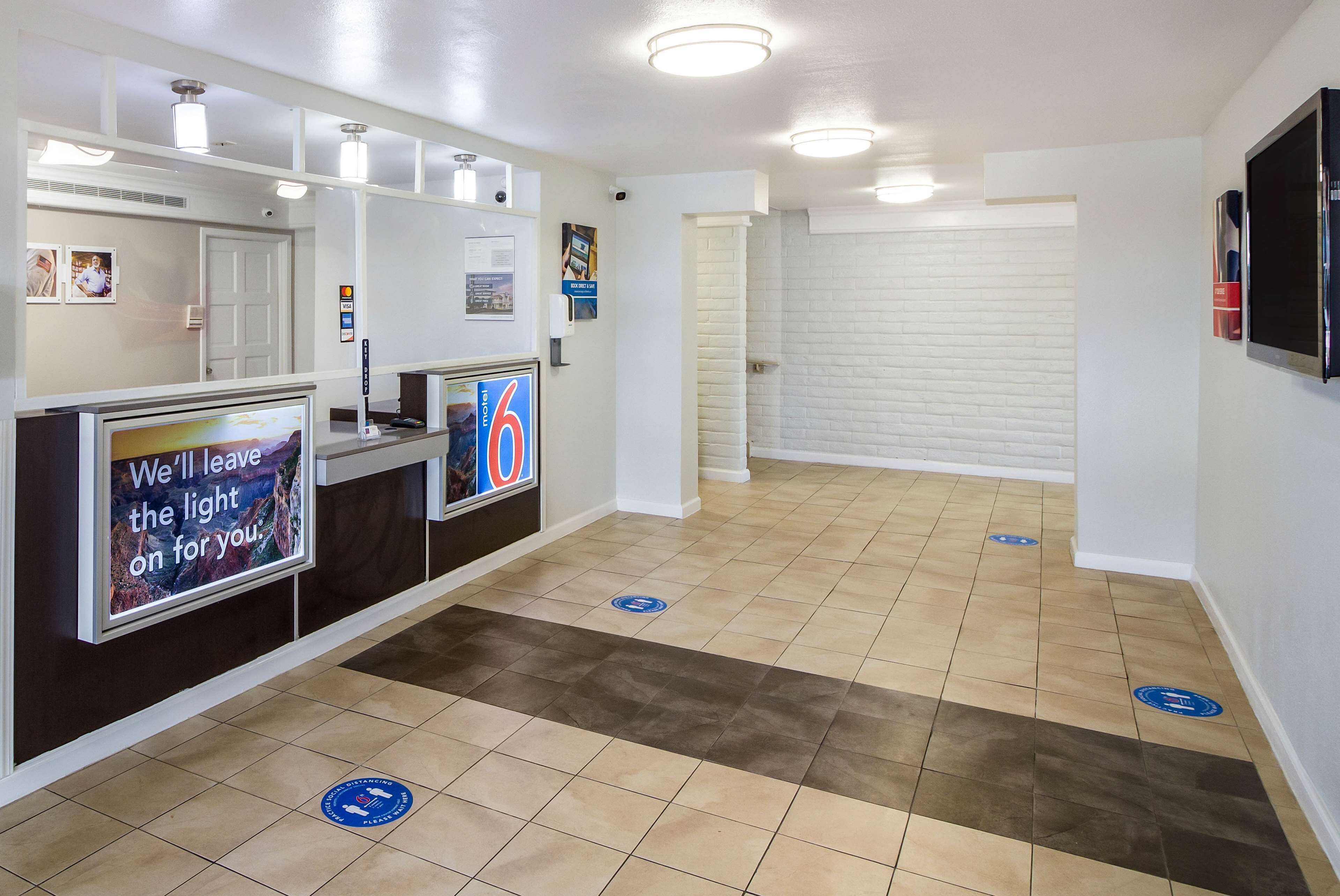 A reception area with a counter, a digital screen, and a sign that reads "We'll leave the light on for you."