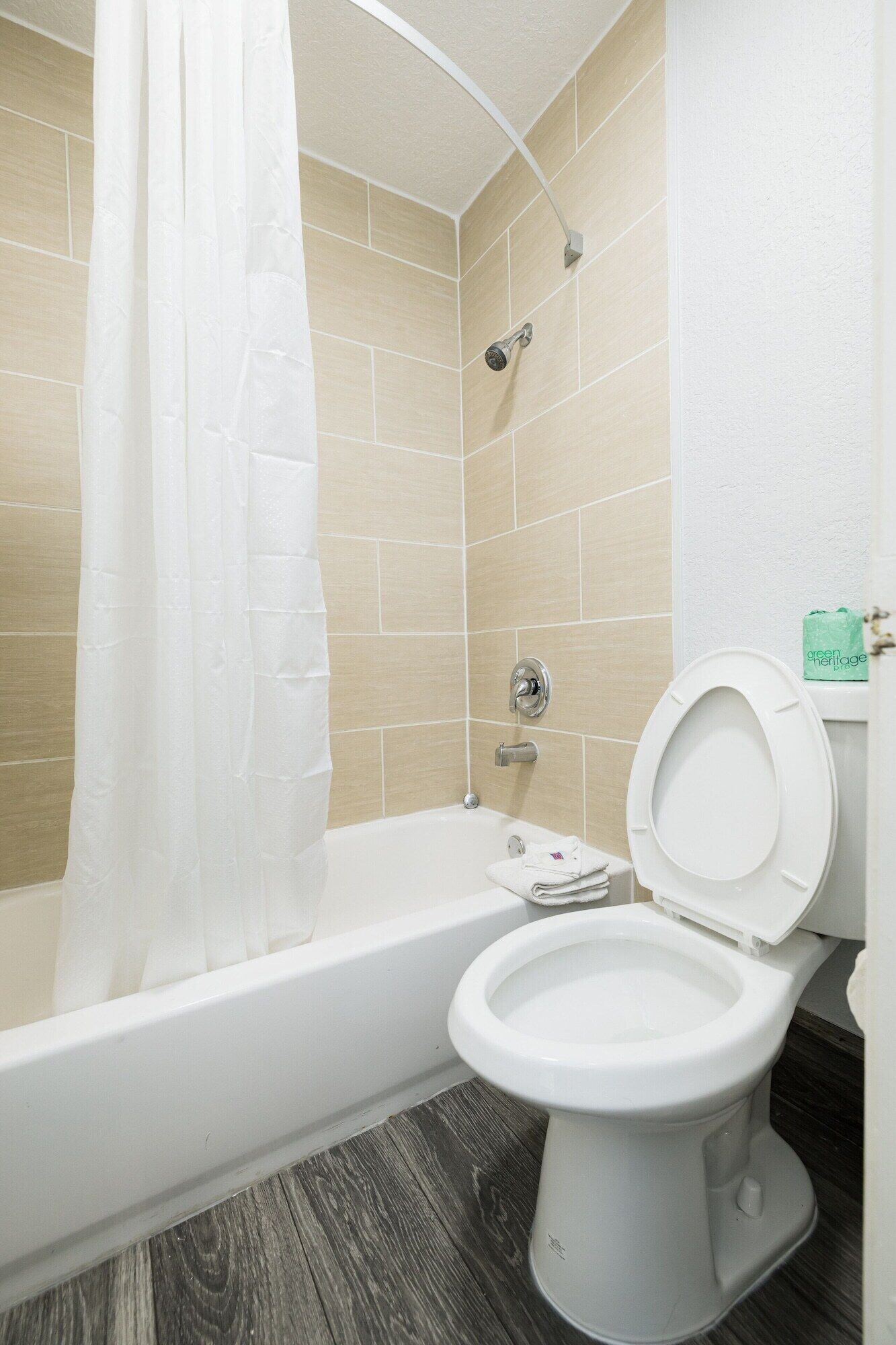 A bathroom with a bathtub, toilet, and shower curtain.