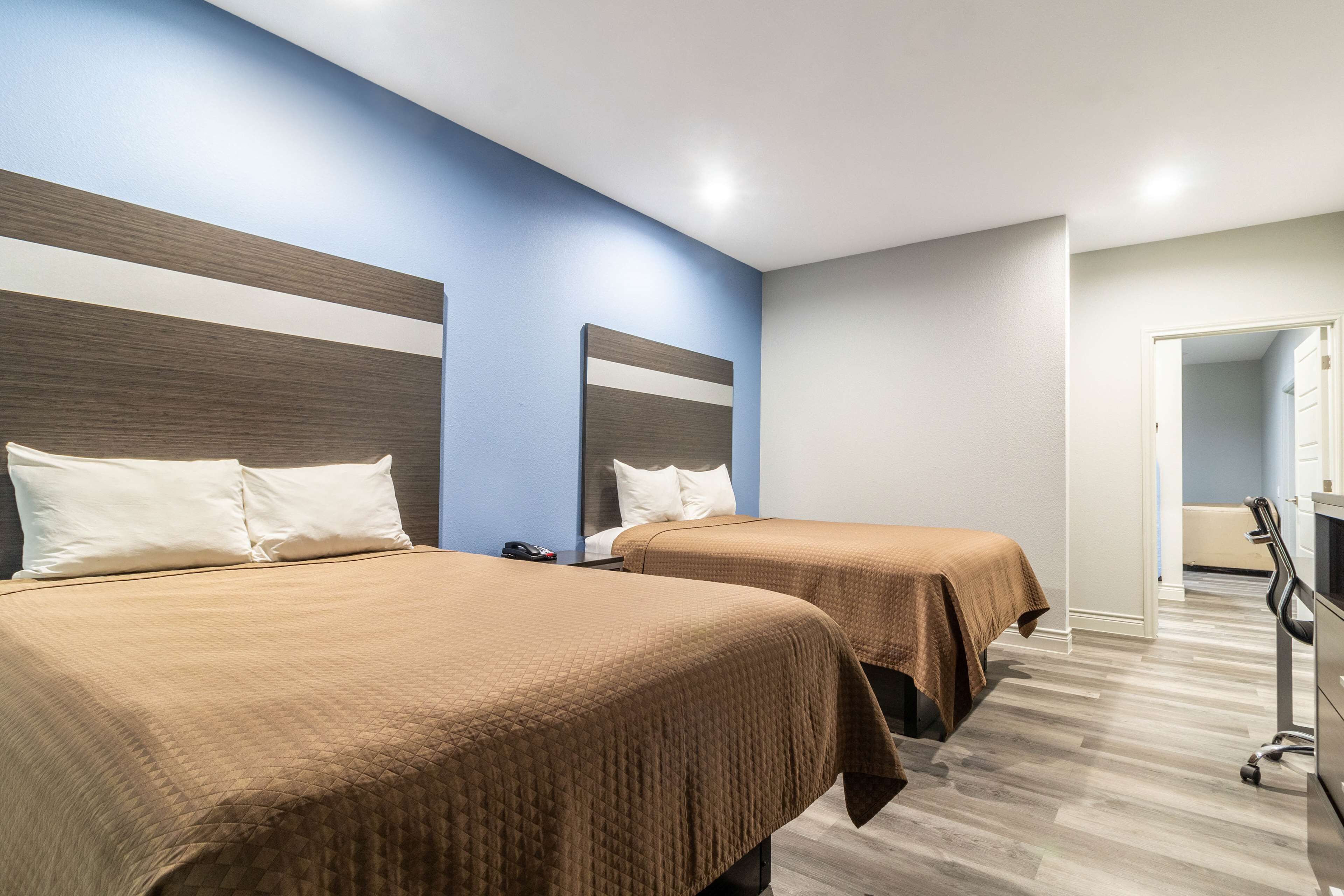 Habitación de hotel con dos camas, un escritorio y una silla.
