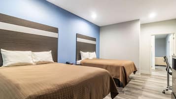 Habitación de hotel con dos camas, un escritorio y una silla.