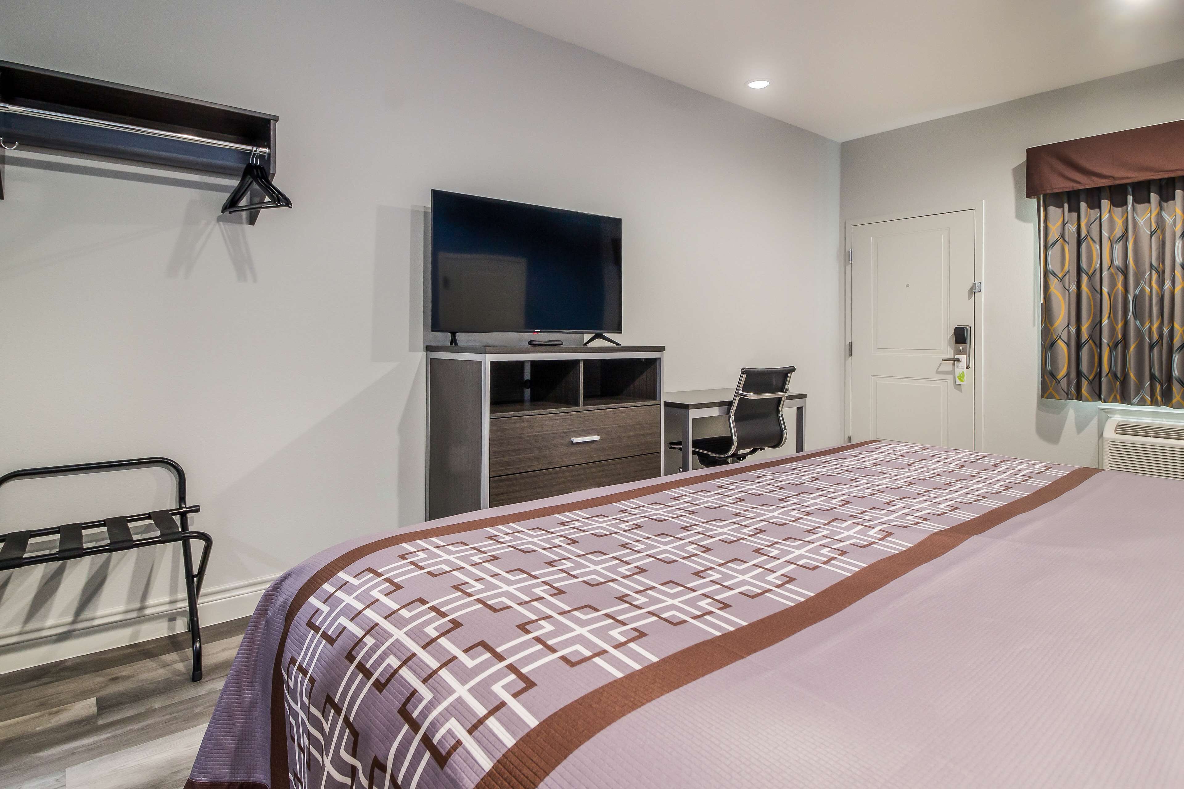 A bedroom with a bed, a desk, a chair, a wardrobe, and a television.