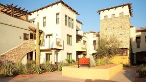 Un patio con un cactus, un letrero que dice "City of Arches" y edificios con fachadas de piedra y estuco.