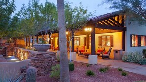 Un espacio de patio con muros de piedra, una chimenea y mobiliario exterior.