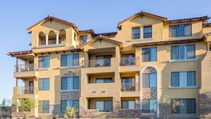 Un edificio residencial de varios pisos con balcones, ventanas grandes y techo plano.