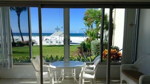 A room with a view of the beach, a round table with chairs, and a sofa. - Island House Beach Resort 2N (Siesta Key)