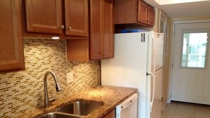 A kitchen with two stainless steel sinks, wooden cabinets, a white refrigerator, and a tiled backsplash. - Island House Beach Resort 2N (Siesta Key)