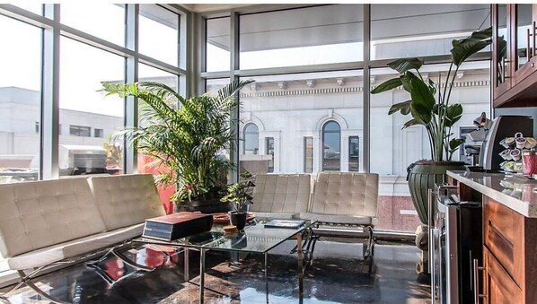 Relax in a spacious room with a seating area, featuring a cushioned bench and glass-top table.