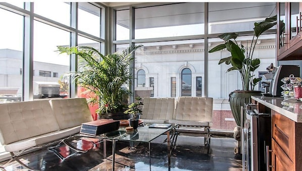 Relax in a spacious room with a seating area, featuring a cushioned bench and glass-top table.