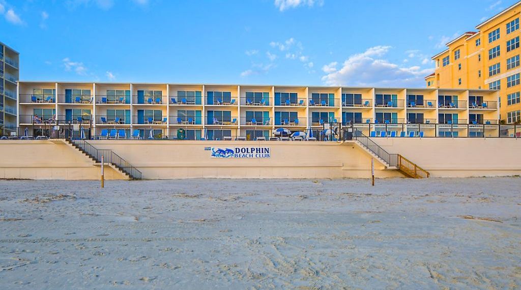A Dolphin Beach Club building with multiple balconies and a sandy beach in front.