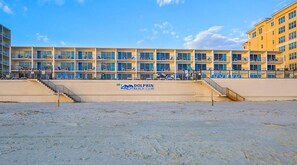 Ein Gebäude des Dolphin Beach Club mit mehreren Balkonen und einem Sandstrand davor.
