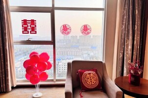 Una habitación con un ventanal amplio, un sofá con un cojín y una mesa con un florero.