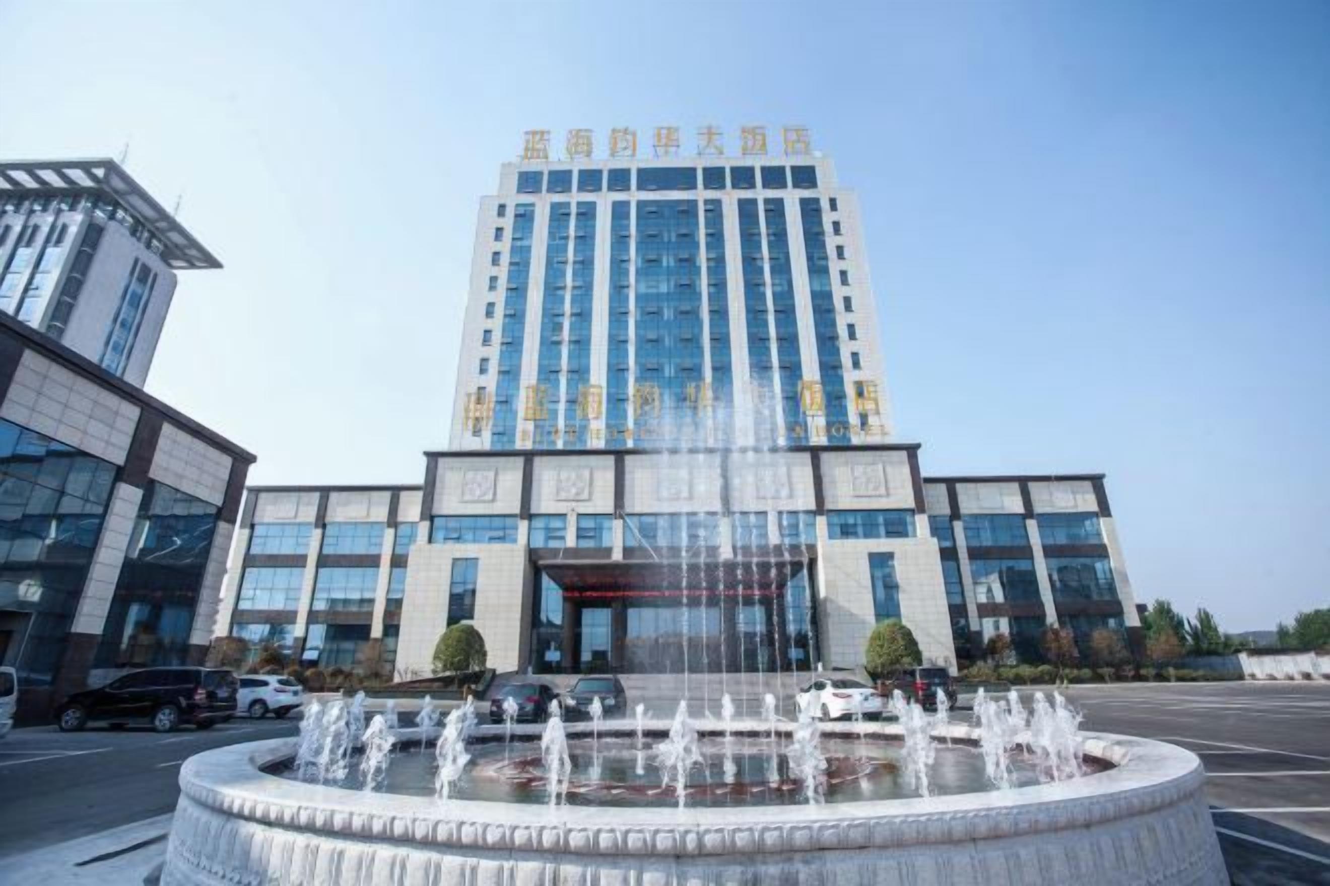 A modern building with a central fountain, large windows, and a clear sky.